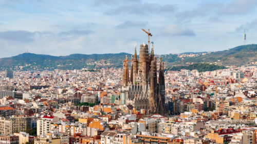 Aerial drone view of Sagrada Familia in city downtown. Famous residential districts around, greenery - Starpik