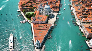 Aerial drone view of Venice, Italy. Water channels with multiple floating and moored boats, historical city centre with Santa Maria della Salute and other old buildings and narrow streets - Starpik