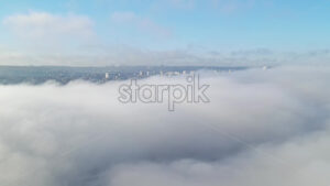 Aerial drone view above the clouds with buildings visible through, Chisinau, Moldova - Starpik Stock