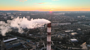Aerial drone view of Chisinau at sunset. Tube of the thermal station with smoke coming out. Industrial zone near it and cityscape on the background. Moldova - Starpik Stock