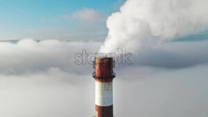 Aerial drone view of Chisinau. Tube of the thermal station with smoke coming out above the low clouds. Visible buildings. Moldova - Starpik Stock