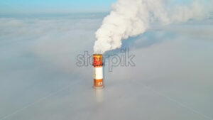 Aerial drone view of Chisinau. Tube of the thermal station with smoke coming out above the low clouds. Visible buildings. Moldova - Starpik Stock