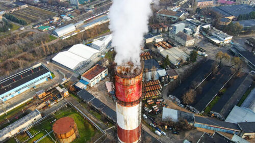 Aerial drone view of Chisinau. Tube of the thermal station with smoke coming out. Industrial zone near it. Cloudy weather. Moldova - Starpik Stock