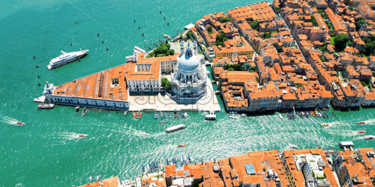 Aerial drone view of Venice, Italy. Water channels with multiple floating and moored boats, historical city centre with Santa Maria della Salute and other old buildings and narrow streets - Starpik Stock