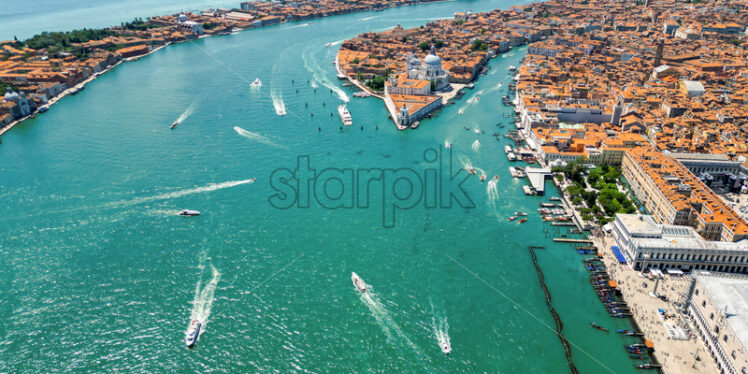 Aerial drone view of Venice, Italy. Water channels with multiple floating and moored boats, historical city centre with Santa Maria della Salute and other old buildings and narrow streets - Starpik Stock
