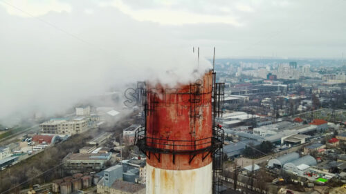 Aerial drone view of thermal station with smoke coming out of the tube. Buildings, roads and bare trees on the background. Cloudy weather. Chisinau, Moldova - Starpik Stock