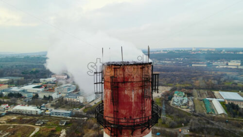 Aerial drone view of thermal station with smoke coming out of the tube. Buildings, roads and bare trees on the background. Cloudy weather. Chisinau, Moldova - Starpik Stock