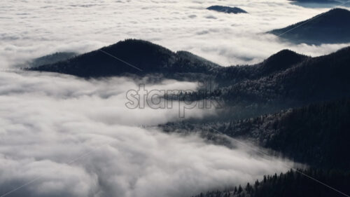 Aerial drone view of winter mountains with fog in Ceahlau National Park, Romania - Starpik Stock