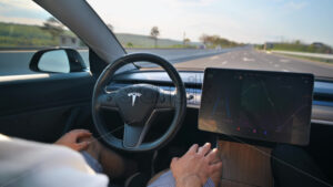 CHISINAU, MOLDOVA – MAY, 2023: Interior view of a Tesla Model 3 moving on autopilot on a highway. Driver periodically touching the steering wheel - Starpik Stock