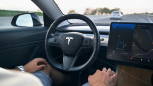CHISINAU, MOLDOVA – MAY, 2023: Interior view of a Tesla Model 3 moving on autopilot on a highway. Driver periodically touching the steering wheel - Starpik Stock
