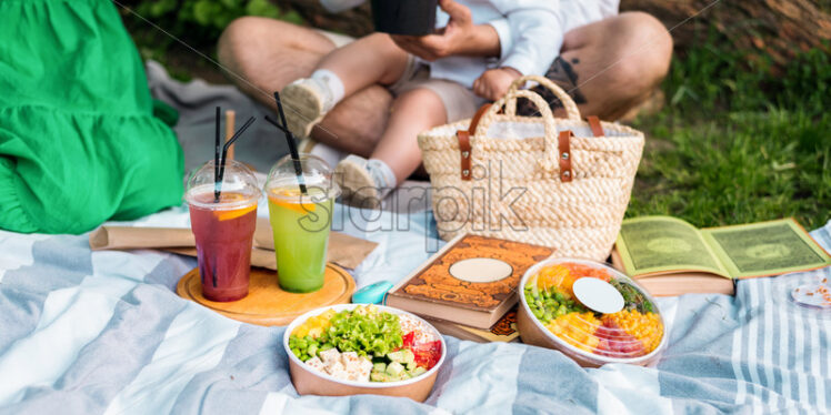 Close view of poke bowls on a blanket, family in the background - Starpik Stock