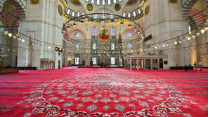 Interior view of the Suleymaniye mosque in Istanbul, Turkey. A lot of illumination, painted ceiling, red carpet - Starpik Stock