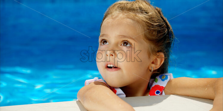 Little girl in sunglasses resting on white pool balloon - Starpik Stock