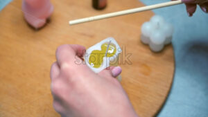 Making candles in a special shape workshop, woman boiling wax - Starpik Stock