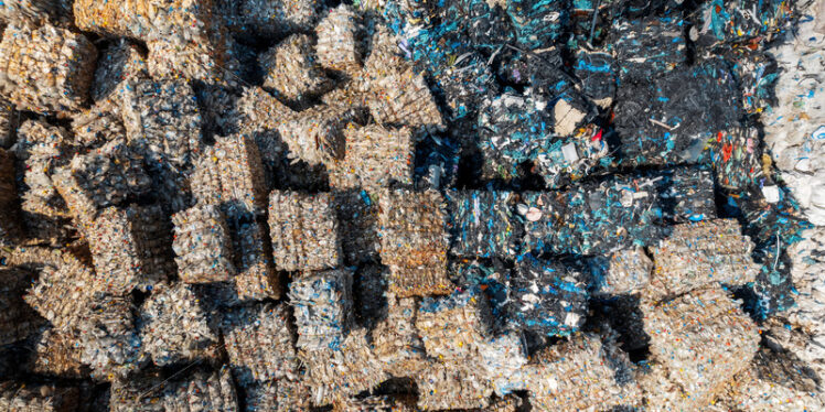 Multiple cubes of compressed plastic garbage near the waste recycling factory in open air. Vertical view - Starpik Stock