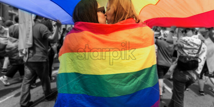 Pride parade in center of Chisinau, Moldova. A couple kissing with rainbow flag above - Starpik Stock