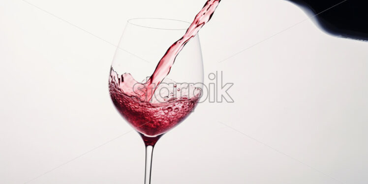 Red wine is poured into a glass, white background - Starpik Stock