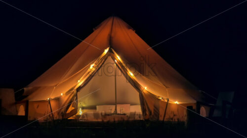 Tent interior and exterior with lamps, bed and furniture at glamping, night - Starpik