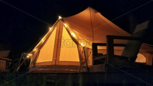 Tent with lamps and wooden chair at glamping, night - Starpik