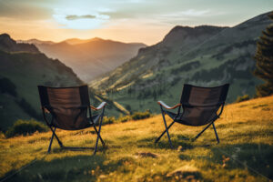 Two folding chairs sitting on a meadow and in the distance an amazing view of some mountain ranges - Starpik Stock