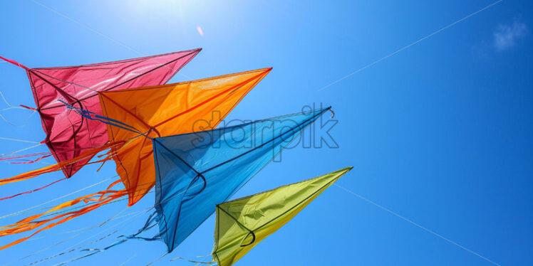 A series of colorful kites soaring high in the clear, blue sky - Starpik Stock