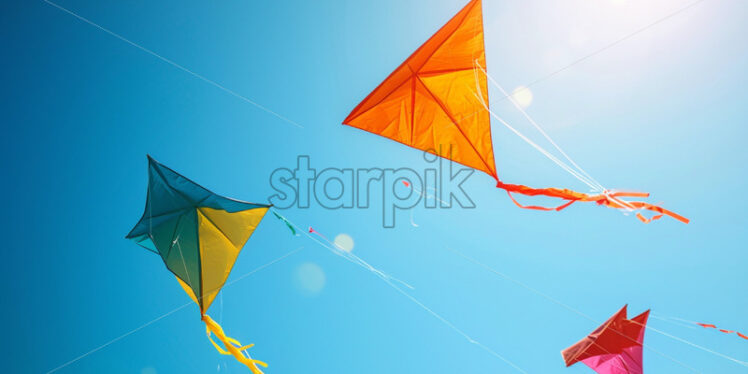 A series of colorful kites soaring high in the clear, blue sky - Starpik Stock