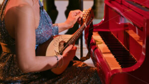 VIDEO Dressed-up woman playing the mandolin near a red piano - Starpik