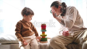 VIDEO Father playing with his son with colourful, ecological wooden toys near a window - Starpik