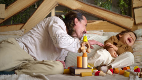 VIDEO Father playing with his son with colourful, ecological wooden toys on the bed - Starpik