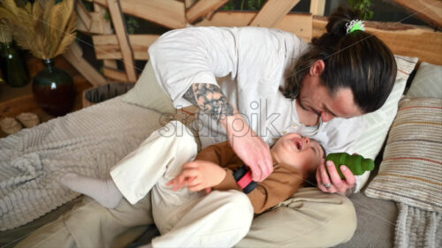 VIDEO Father playing with his son with colourful, ecological wooden toys on the bed - Starpik