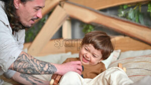 VIDEO Father playing with his son with colourful, ecological wooden toys on the bed - Starpik