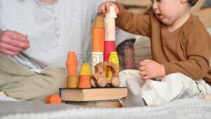 VIDEO Father playing with his son with colourful, ecological wooden toys on the bed - Starpik