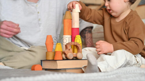 VIDEO Father playing with his son with colourful, ecological wooden toys on the bed - Starpik