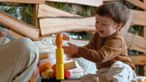 VIDEO Man playing with child with colourful wooden toys on the bed - Starpik