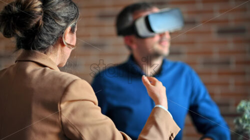 VIDEO Man using a Virtual Reality headset in an office while woman explains and gesticulates - Starpik