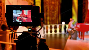 VIDEO Professional camera filming a woman playing a red piano on the backstage of a TV set - Starpik