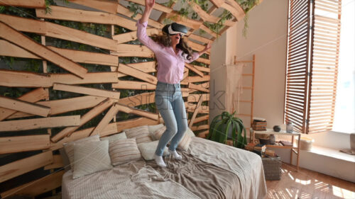 VIDEO Woman looking through VR headset and jumping on bed - Starpik