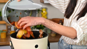 VIDEO Woman throwing vegetables peels in a compost bin from a collection vessel. Housewife cooking food and composting organic waste in a bokashi container at home. Ecological and sustainability concept - Starpik