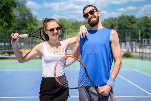 Portrait of a happy young couple holding tennis rackets - Starpik