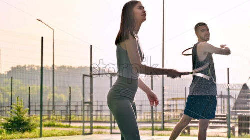 VIDEO A man and a woman practicing tennis at sunset, after rain - Starpik