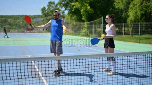 VIDEO A man teaching a woman how to play pickleball on a sunny day - Starpik