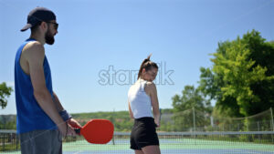 VIDEO A man teaching a woman how to play pickleball on a sunny day - Starpik
