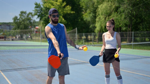 VIDEO A man teaching a woman how to play pickleball on a sunny day - Starpik