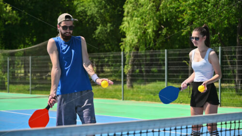 VIDEO A man teaching a woman how to play pickleball on a sunny day - Starpik