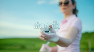 VIDEO Close up of a woman in white and pink clothes holding a white golf ball on the course - Starpik