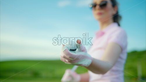 VIDEO Close up of a woman in white and pink clothes holding a white golf ball on the course - Starpik