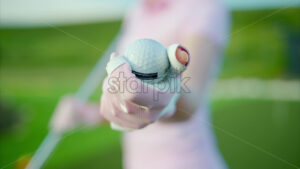 VIDEO Close up of a woman in white and pink clothes holding a white golf ball on the course - Starpik