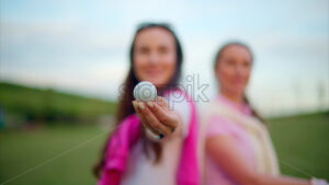 VIDEO Close up of two women in white and pink clothes holding a white golf ball on the course - Starpik