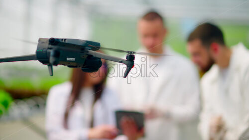 VIDEO Drone filming three laboratory technicians in white coats working with plants grown with the Hydroponic method in a greenhouse - Starpik