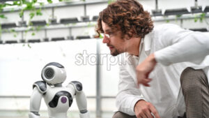 VIDEO Laboratory technician in a white coat interacting with humanoid robot in a greenhouse farm - Starpik